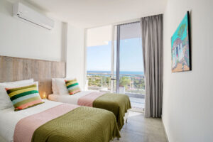two beds in a room with a view of the ocean