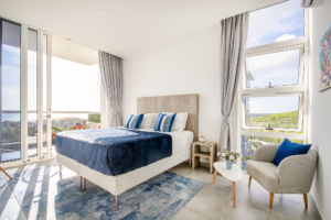 a sunny bedroom with a bed and chairs